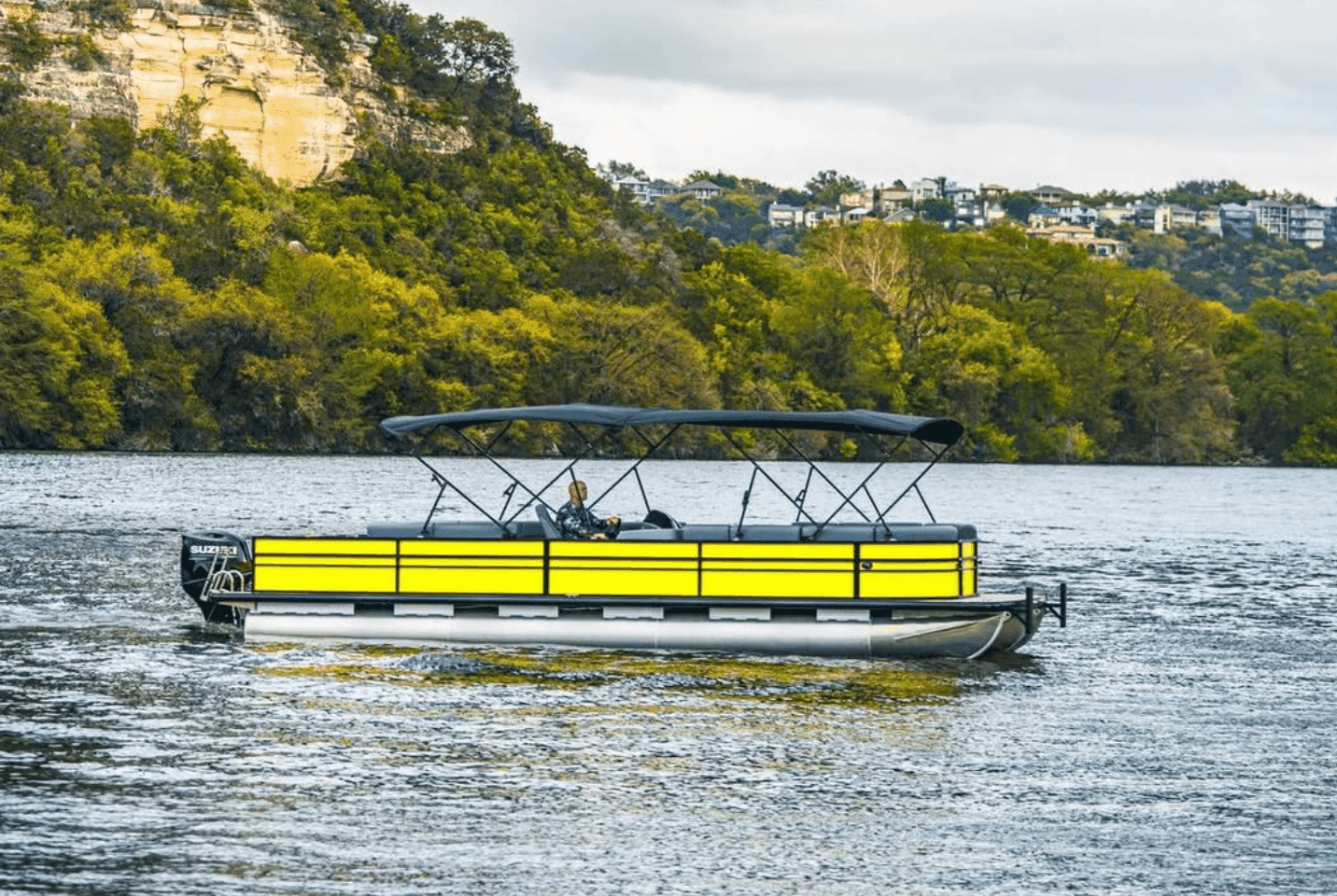 Yellow pontoon boat on scenic Lake Travis